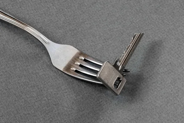 Masanın çatalındaki gri arkaplandaki metal anahtar. Yemeğin anahtarı..