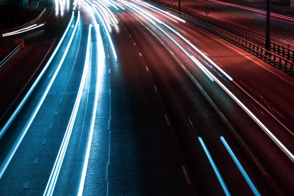 White blue and red lights of a car in motion at long exposure on a night highway. Background with stripes.