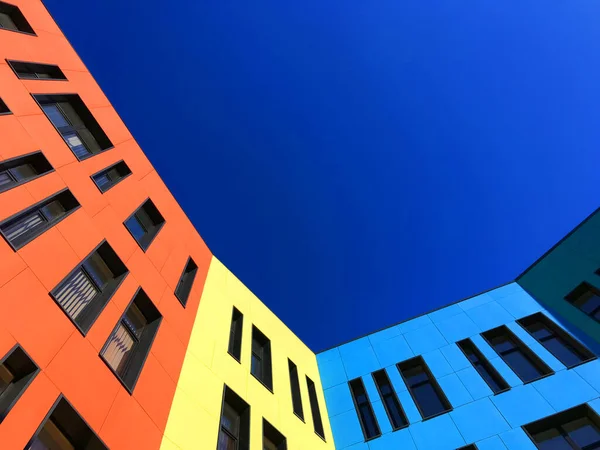 Okulun çok renkli yüzleri ve siyah pencere çerçeveleri. Mavi gökyüzünden yukarı bak