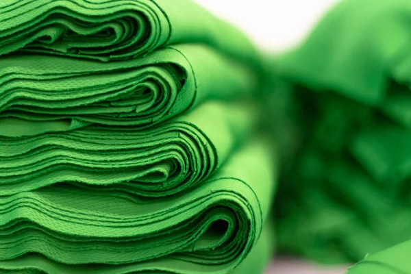 Kumaş spor örgüsü, parlak yeşil renkli yakın çekim yığınına katlandı. Dikiş endüstrisi.