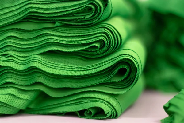 Kumaş spor örgüsü, parlak yeşil renkli yakın çekim yığınına katlandı. Dikiş endüstrisi.