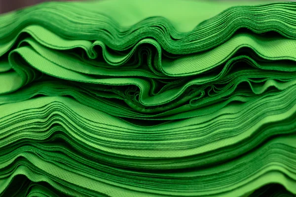 Kumaş spor örgüsü, parlak yeşil renkli yakın çekim yığınına katlandı. Dikiş endüstrisi.