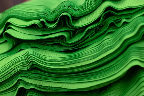 Kumaş spor örgüsü, parlak yeşil renkli yakın çekim yığınına katlandı. Dikiş endüstrisi.