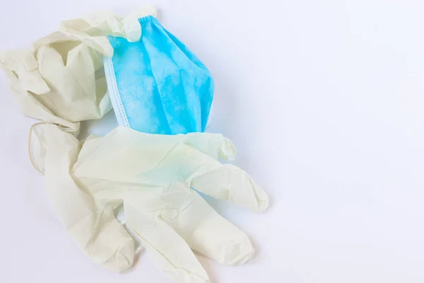 Used, infected with the virus, covid individual white disposable gloves and a medical blue mask are thrown away unnecessary. Ecology problem, non-recyclable, recyclable, infected with a virus