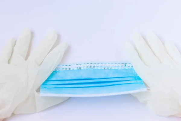 Mavi maske takan bir çift beyaz lateks eldiven. Bir doktor ya da virüslü basit bir insan için ilaçlar.