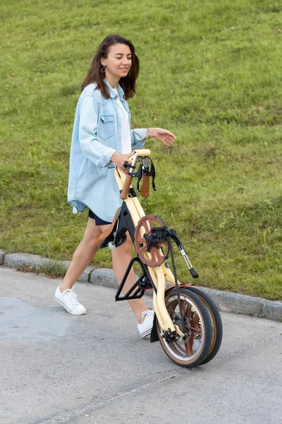 Güzel genç bir kadın katlıyor ve bir bisikleti açıyor. Seyahat ve ulaşım için uygun katlama motoru.