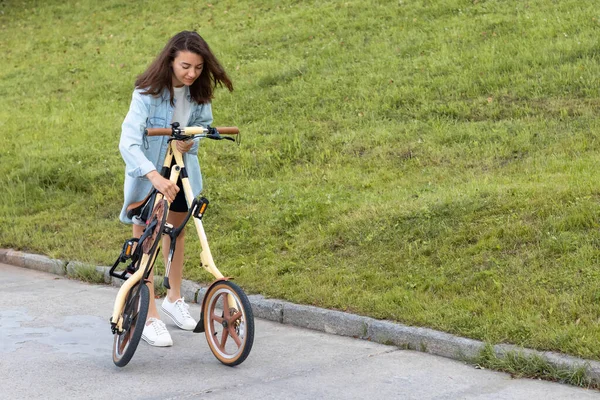 Güzel genç bir kadın katlıyor ve bir bisikleti açıyor. Seyahat ve ulaşım için uygun katlama motoru.