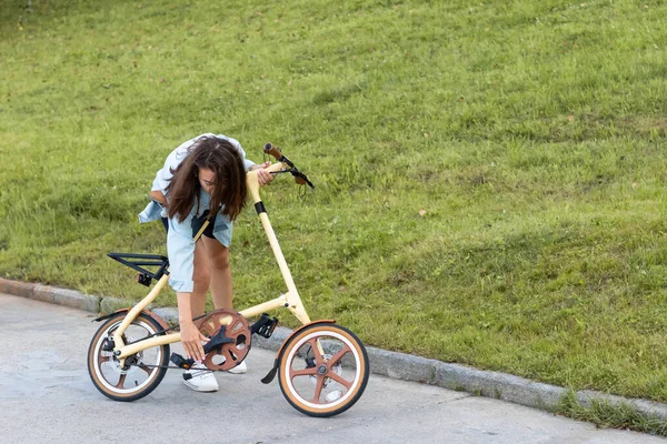 Güzel genç bir kadın katlıyor ve bir bisikleti açıyor. Seyahat ve ulaşım için uygun katlama motoru.