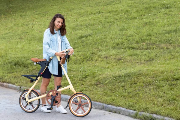 Güzel genç bir kadın katlıyor ve bir bisikleti açıyor. Seyahat ve ulaşım için uygun katlama motoru.