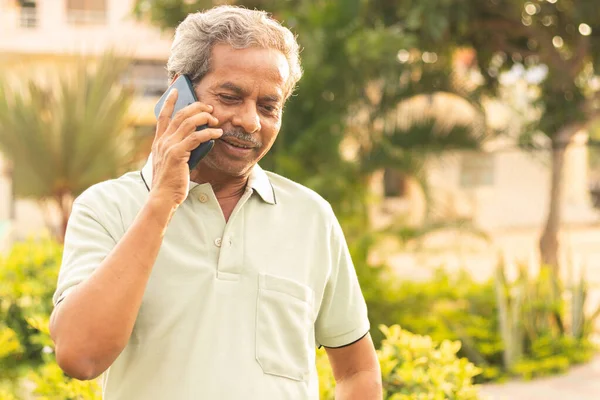 Gezond senior Aziaat aan de telefoon outdoor green park - Oudere man bezig in mobiel - Gelukkig mannelijk ouder praten over de telefoon. — Stockfoto