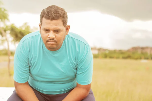 Poważnie gruby mężczyzna na świeżym powietrzu, park - pojęcie smutku z powodu nadwagi - indyjski otyły człowiek czuje się nieszczęśliwy lub przygnębiony. — Zdjęcie stockowe
