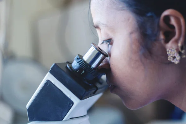 현미경을 조사하느라 분주 한, 실험실 여성 과학자에게 현미경을 사용하는 여성의 근접 사진. — 스톡 사진