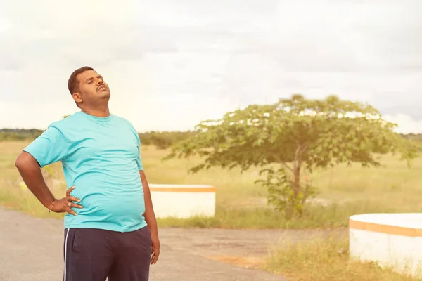 Unavený mladý obézní muž holiding jeho záda při jogging - koncepce tlustého muže fitness a nezdravý životní styl. — Stock fotografie