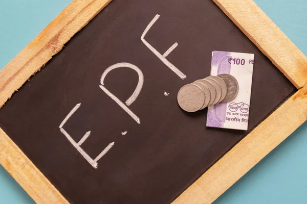 Epf of Employee provident Fund geschreven op zwarte leisteen met Indiase valuta biljetten en munten — Stockfoto