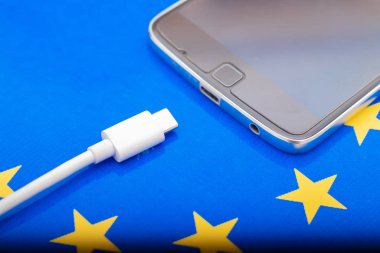Close up Mobile phone Charger with USB Type - C cord on EU Flag