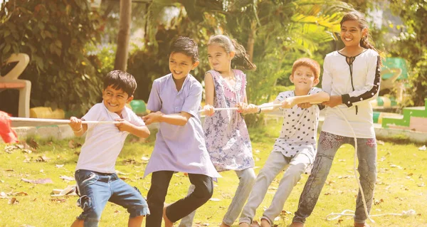 Group of multi racial children playing Tug of war game kindergarten - Multi ethnic kids playing outdoor games against racism. — Stock Photo, Image