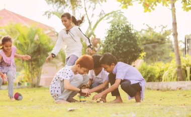 Children playing Lagori, dikori or lagoori outdoor traditional game, where two teams try to hit a pile of stones with ball - concept of kids enjoying outdoor games in technology driven world.