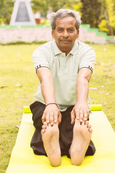낮은 각도, 운동 또는 요가 매트에 앉아 자신의 발가락을 만지는 노인의 전체 시야 - 활동적 인 행복 한 노인 건강 과 건강의 개념 — 스톡 사진