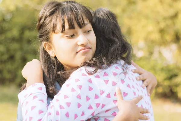 Concepto de abrazo falso, amistad, abrazo o dos caras - Joven adolescente Niña hipócrita abrazando triste amigo en el parque . — Foto de Stock