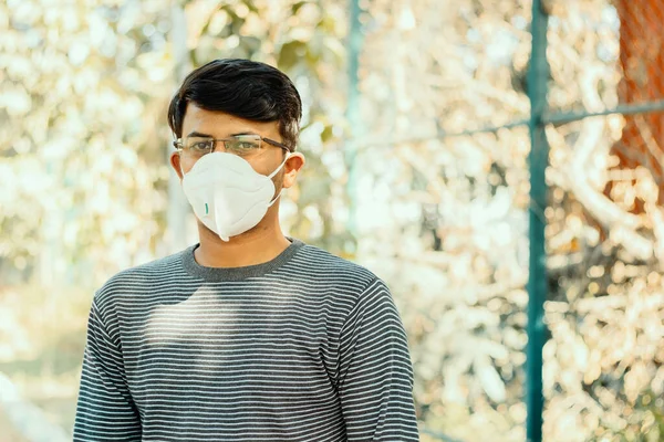 Koronavirüs veya covid-19 salgını nedeniyle N95 tıbbi yüz maskesi takan Asyalı bir adam açık havada, hava kirlenmesinden, koronavirüsten, sars cov 2 veya maske takarak virüs enfeksiyonundan korunan kişi.