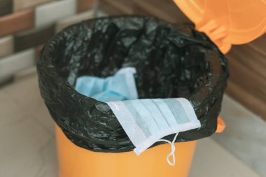 Covid-19, 2019-ncov ya da Coronavirus tıbbi yüz maskesini kapalı çöp kutusuna atmanızı ya da çöpe atmanızı tavsiye eder - hijyen uygulaması yaparken gösterilen konsept.