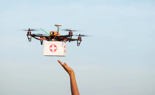 Hands receiving medical aid kit or medicines from drone or quadcopter during covid-19 or coronavirus lockdown - Medical Industry Logistics for Drug Transport concept during lockdown.