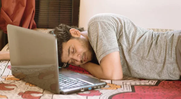 Jovem cansado dormindo na cama com laptop - trabalho duro, preguiça de trabalhar em casa ou WFH durante coronavírus ou covid-19 bloquear conceito . — Fotografia de Stock