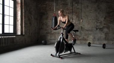 Spor elbiseli kadın yeşil spor salonundaki egzersiz bisikletinde çalışıyor. Spor elbiseli kadın spor salonunda çalışıyor.