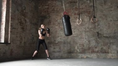 Spor salonunda birlikte antrenman yapan mutlu bir kadın. Spor kulübünde konsantre fitness kadın boks çantası. Spor salonunda eldivenlerle gülümseyen kız boksu..