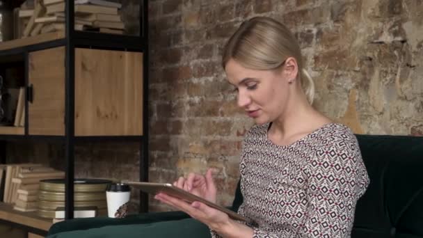 Genç Çekici Gülümseyen Beyaz Kadın Evdeki Kanepede Otururken Tablet Kullanıyor — Stok video