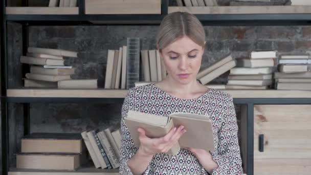 Kütüphanedeki Kitapların Arasında Dururken Eski Kitabın Sayfalarını Çeviren Genç Güzel — Stok video