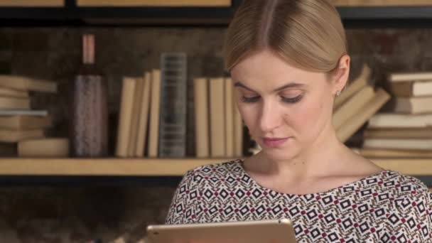 Εμφανίσιμη Γυναίκα Που Χρησιμοποιεί Ένα Tablet Κοντά Στη Βιβλιοθήκη Όμορφη — Αρχείο Βίντεο