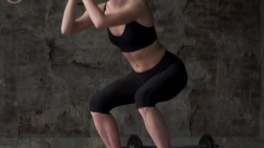 Genç ve güzel bir kız spor salonunda çömeliyor. Bacakları kapat, 4K. Spor anlayışı ve sağlıklı yaşam tarzı. Genç ve güzel bir kız spor salonunda çömeliyor..