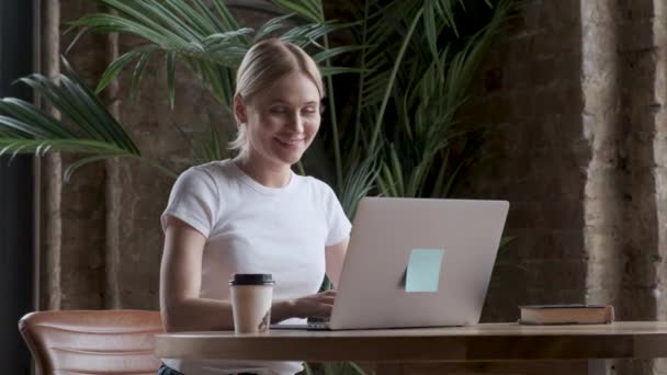 ラップトップ コンピューターで作業して幸せな実業家 笑顔の女性がオフィスにあるコンピューターでの作業の肖像 自宅の作業場でのラップトップを見て女性従業員 — ストック動画