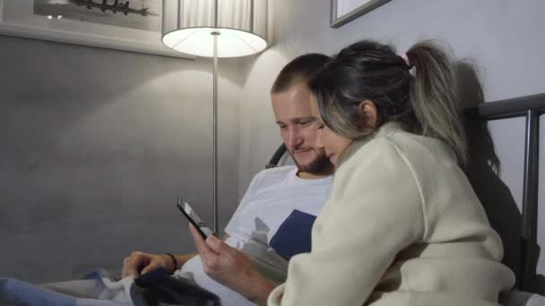카프카스 아내는 차림으로 조용히 침대에 머리를 숙이고 스마트폰을 — 비디오
