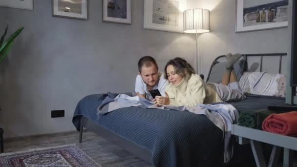매력적 남녀와 침대에 앉아서 녹화를 하면서 스마트폰을 서로를쳐다보고 있습니다 — 비디오