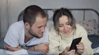 Canlı yayında cep telefonu kullanan çift, yatakta arkadaşlarıyla görüntülü konuşma, hoşça kal dokuması. Beyaz erkek ve kadın..