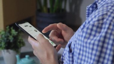 Adam Smartphone 'da Uygulamalı Yemek Siparişi Veriyor. Genç adam yeni evinde yerde otururken akıllı telefon kullanıyor.