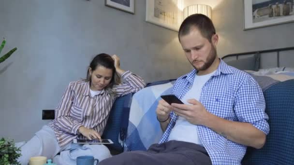 快乐的年轻夫妇拿着手机 看着屏幕 坐在现代房间的地板上 男人和女人都在家里 — 图库视频影像