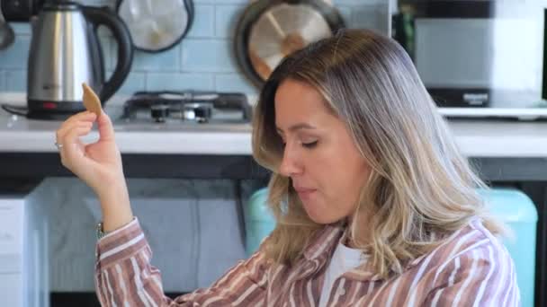 Ekose Gömlekli Uzun Saçlı Kurabiye Yiyen Mutfak Masasında Kitap Okuyan — Stok video
