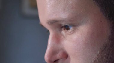 Siyah bir arka planda bilgisayarın başında çalışan genç bir adamın gözleri ve yüzü yakın plan..