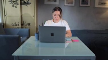 Businesswoman working on laptop computer at home. Woman using laptop on kitchen