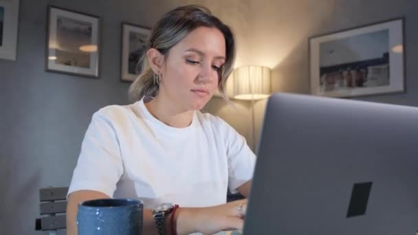 带着笔记本电脑在家里工作的女人 女性博主在投资笔记本电脑上打字 坐在家里的桌子旁边 — 图库视频影像