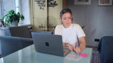 Mutfakta otururken dizüstü bilgisayarda çalışan çekici genç bir kadının yakın çekimi. Stok görüntüleri. Modern.