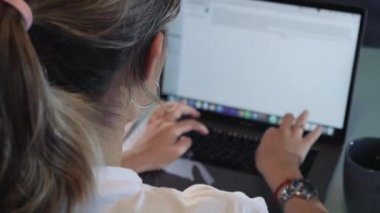 Beautiful young woman lies in bed, uses laptop for work or chat online.