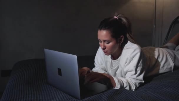 女人在现代旅馆公寓里吃早餐 身穿浴衣的少女躺在床上 用笔记本电脑工作 茶壶的焦点盘 — 图库视频影像