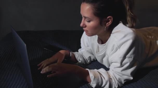 Mujer Joven Utiliza Ordenador Portátil Mientras Está Acostado Cama Chica — Vídeo de stock