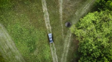 Ormanda kır yolunda uçan beyaz arabanın görüntüsü. Çakıl taşlı yol ormanlarında uçan insansız hava aracı görüntüleri.