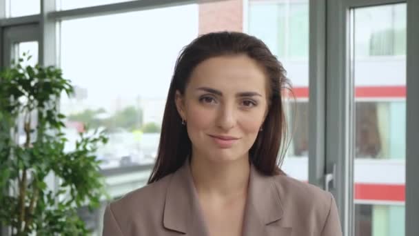 年轻迷人的女企业家面带微笑地看着独自站在现代办公室的相机的画像 — 图库视频影像