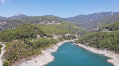 Temiz yeşil suyu ve kıyı manzarasında büyük taşları olan güzel bir dağ gölü.